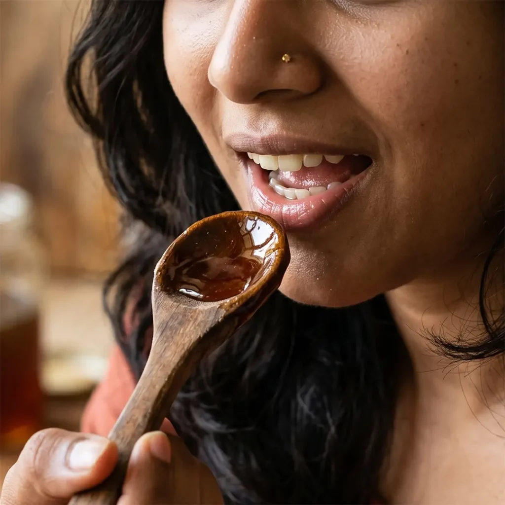 A woman tasting raw honey from a wooden spoon, highlighting the texture and rich color of natural honey.
