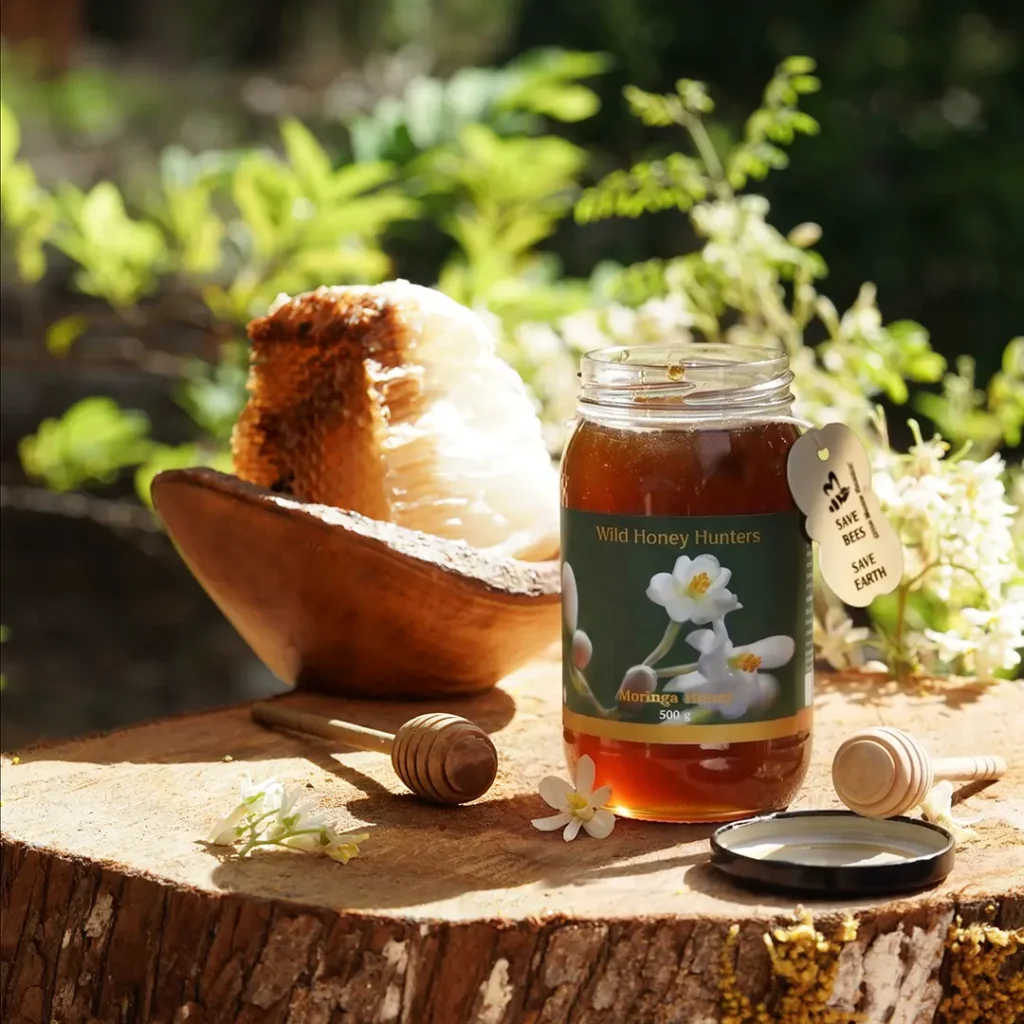 Jar of raw Moringa honey with fresh honeycomb, showcasing pure natural wild honey harvested from forests.